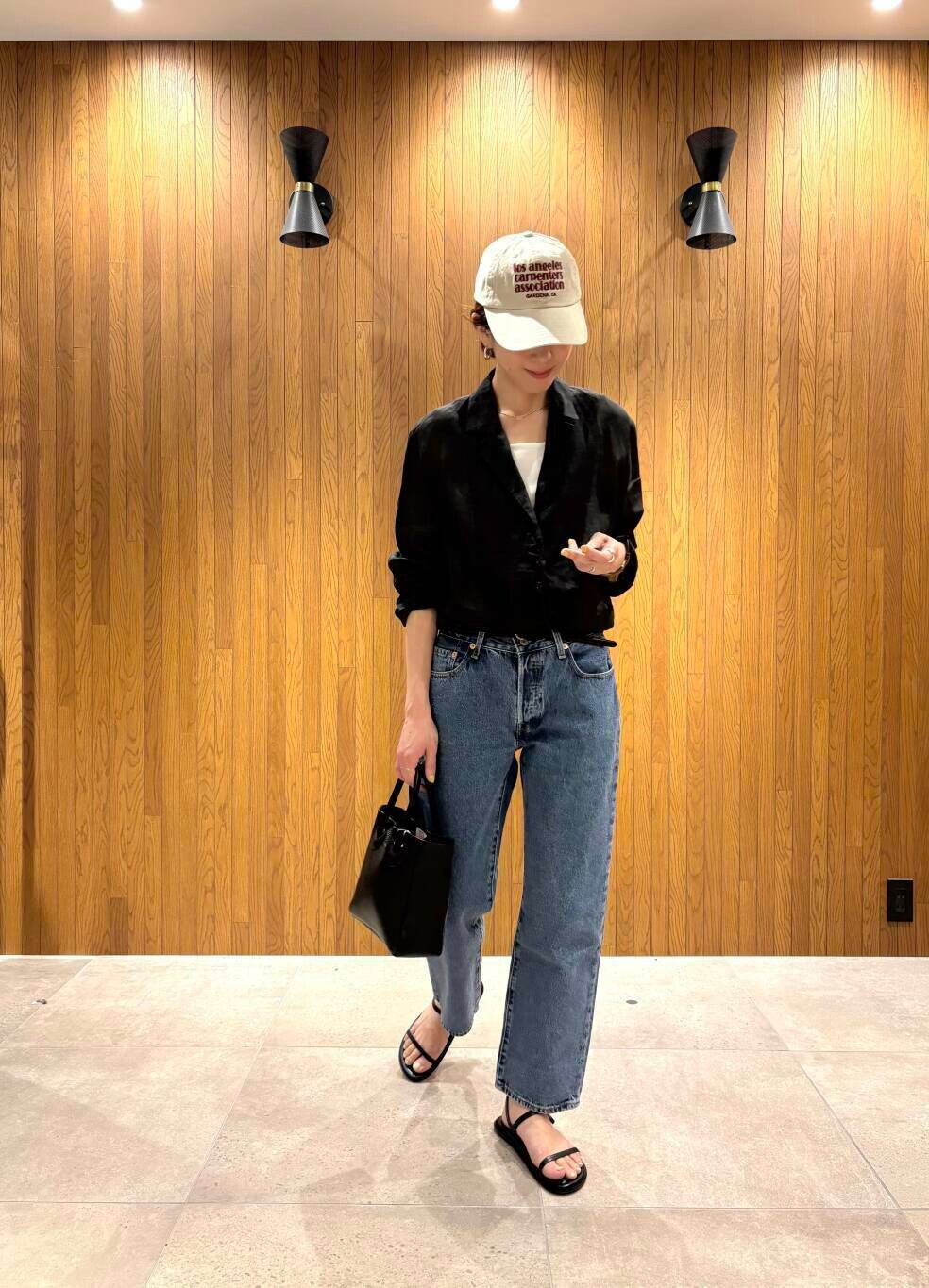 ブラック系のその他アウター、ブルー系のデニムパンツ、ベージュ系のキャップを着用したレディースの春コーディネートの4枚目の写真