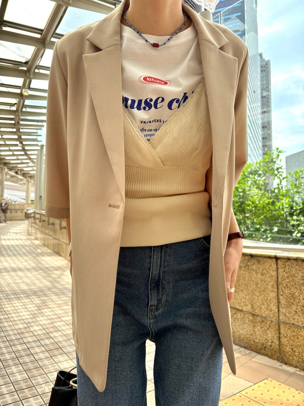 ブルー系のデニムパンツ、ベージュ系のその他アウター、ブラック系のハンドバッグを着用したレディースの春コーディネートの6枚目の写真