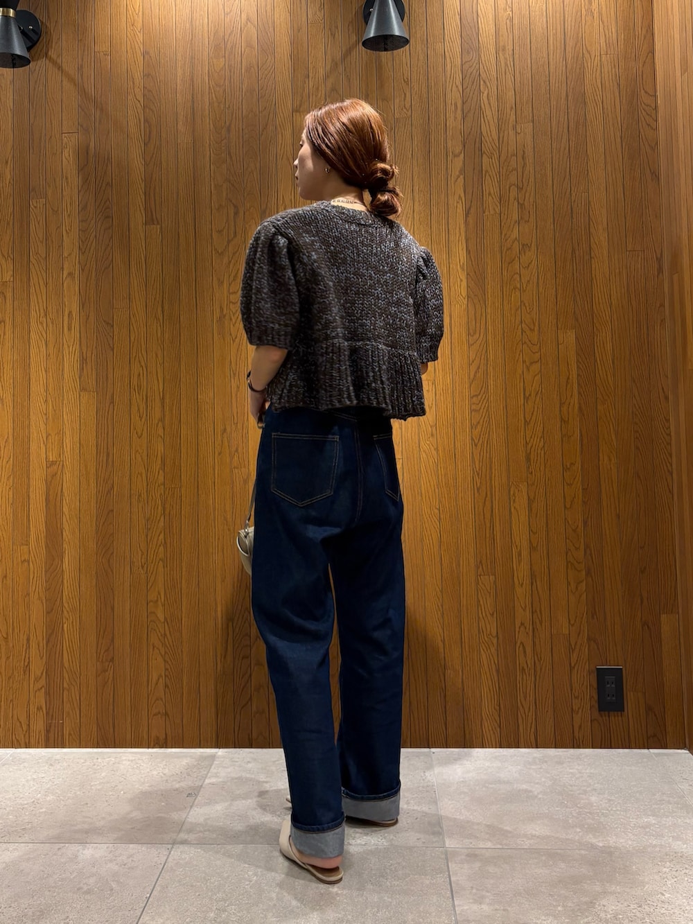 ブルー系のデニムパンツ、ブラウン系のニット/セーター、ベージュ系のハンドバッグを着用したレディースの秋コーディネートの3枚目の写真