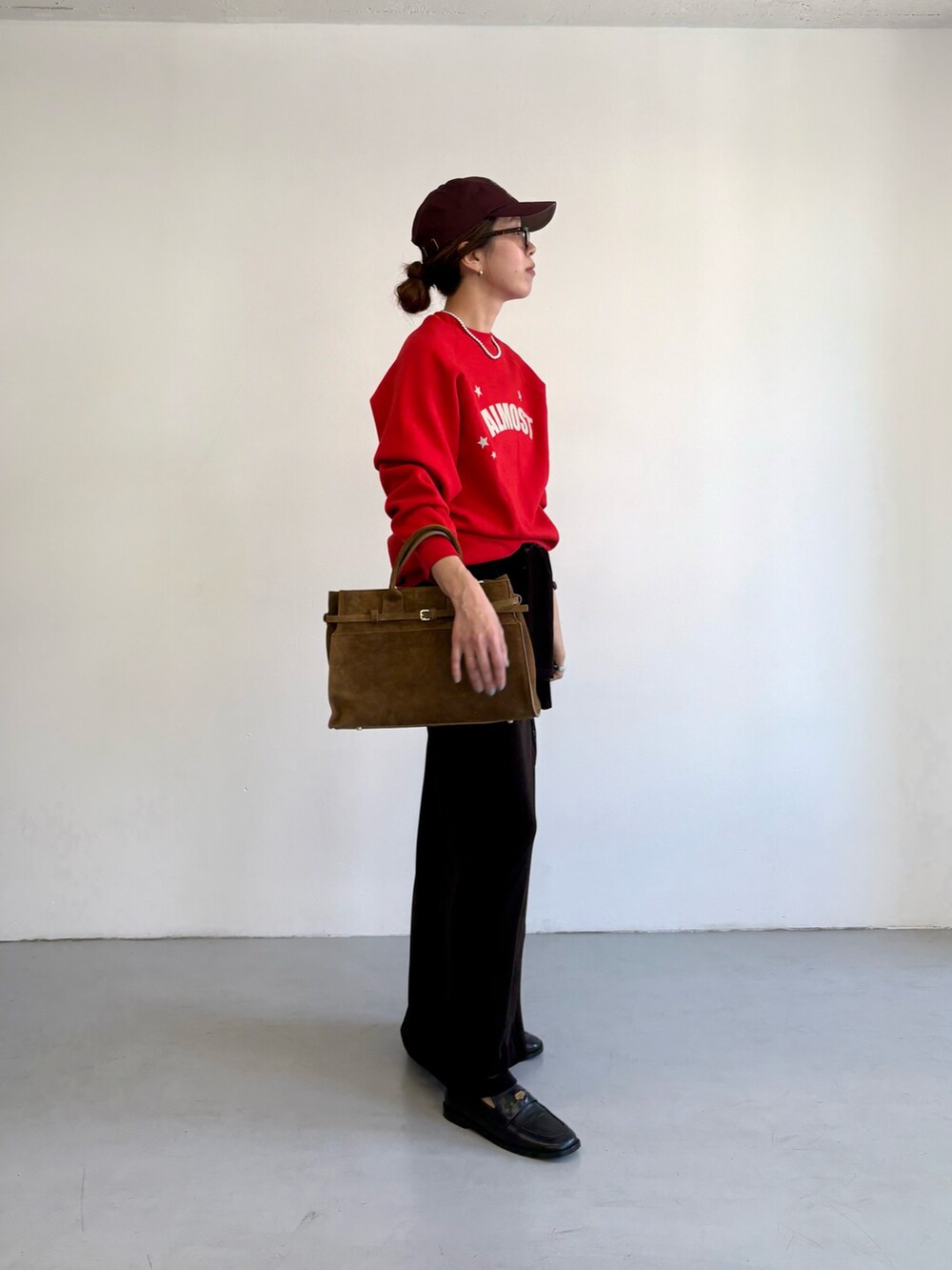 レッド系のスウェット、ブラウン系のトートバッグ、ブラック系のローファーを着用したレディースの秋コーディネートの3枚目の写真