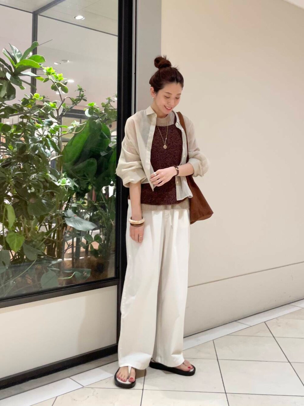 イエロー系のニット/セーター、ホワイト系のその他パンツ、ブラウン系のキャミソールを着用したレディースの春コーディネートの5枚目の写真