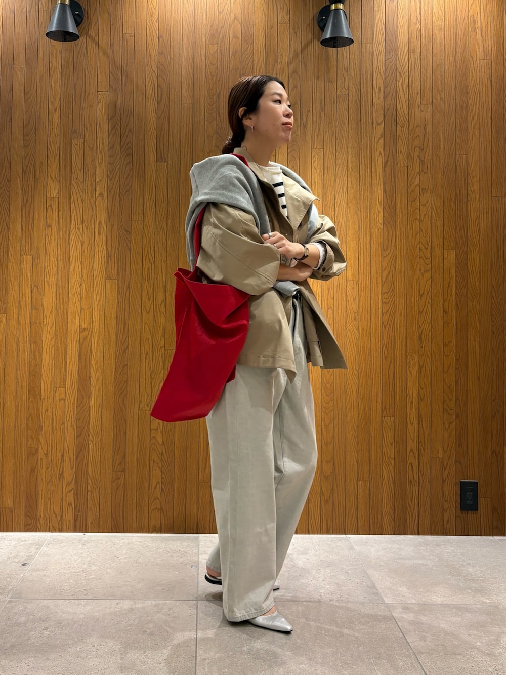 ベージュ系のトレンチコート、グレー系のデニムパンツ、シルバー系のパンプスを着用したレディースの冬コーディネートの2枚目の写真