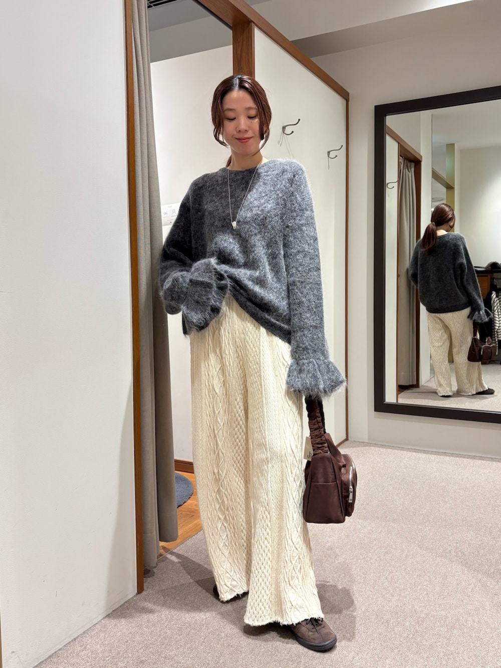 レッド系のショルダーバッグ、グレー系のニット/セーターを着用したレディースの冬コーディネートの4枚目の写真