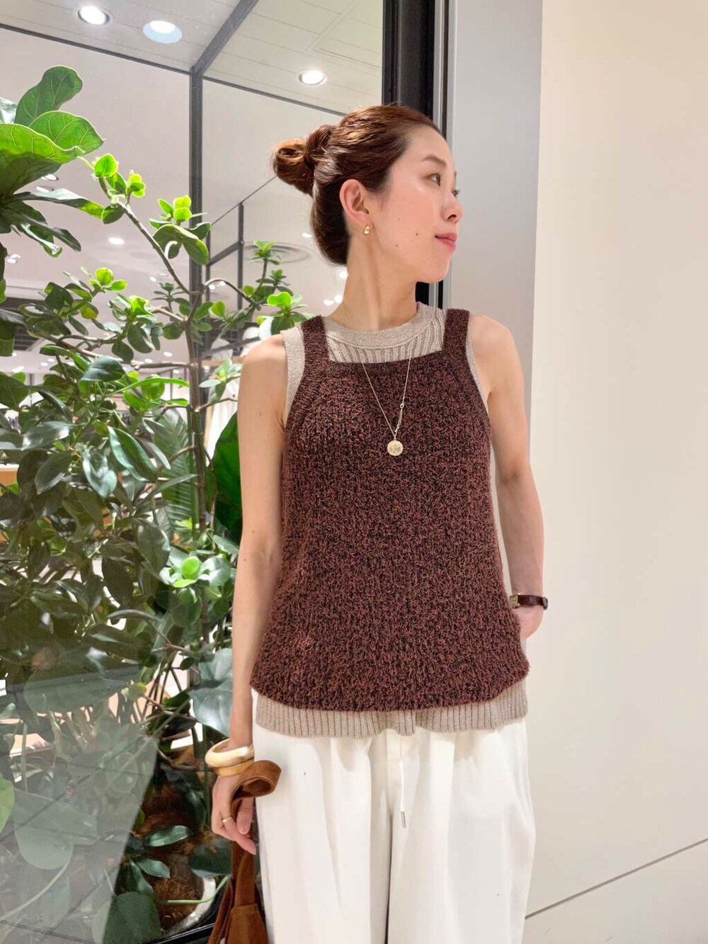 イエロー系のニット/セーター、ホワイト系のその他パンツ、ブラウン系のキャミソールを着用したレディースの春コーディネートの7枚目の写真