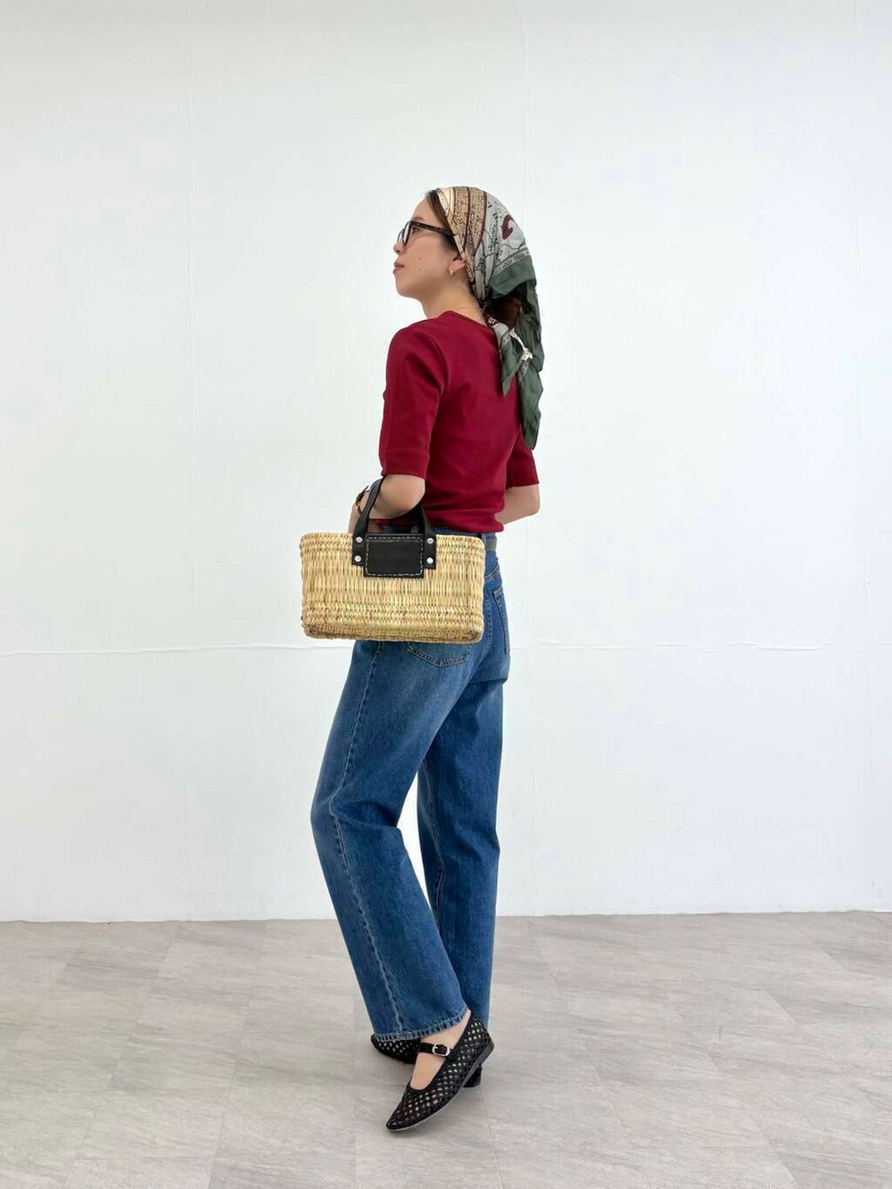 ブラック系のかごバッグ、ブルー系のデニムパンツ、レッド系のTシャツ/カットソーを着用したレディースの夏コーディネートの3枚目の写真
