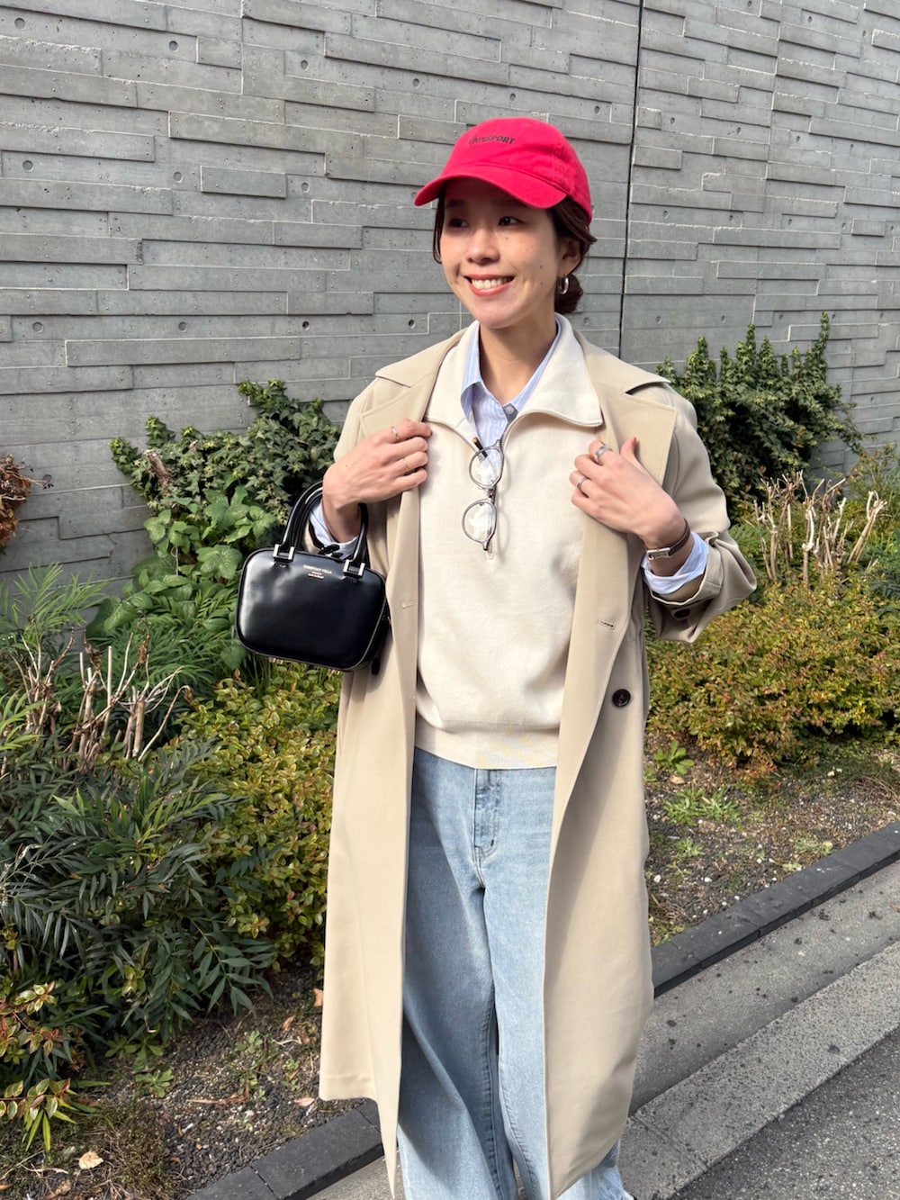 ベージュ系のトレンチコート、グレー系のデニムパンツ、ブラック系のショルダーバッグを着用したレディースの冬コーディネートの5枚目の写真