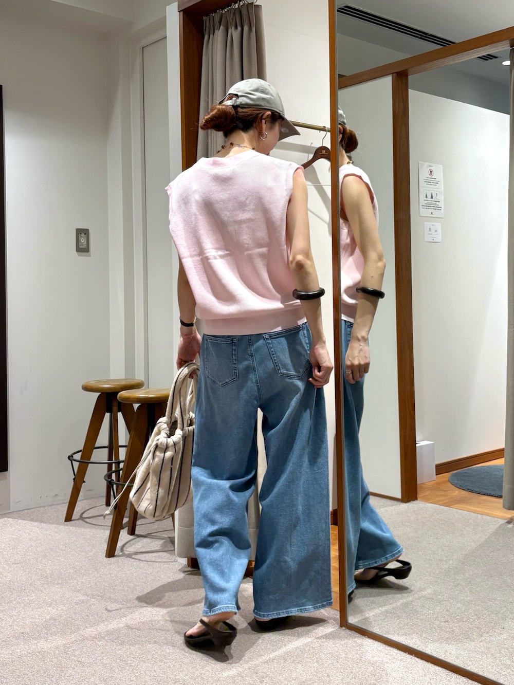 ブルー系のデニムパンツ、ピンク系のベスト、ホワイト系のハンドバッグを着用したレディースの夏コーディネートの4枚目の写真