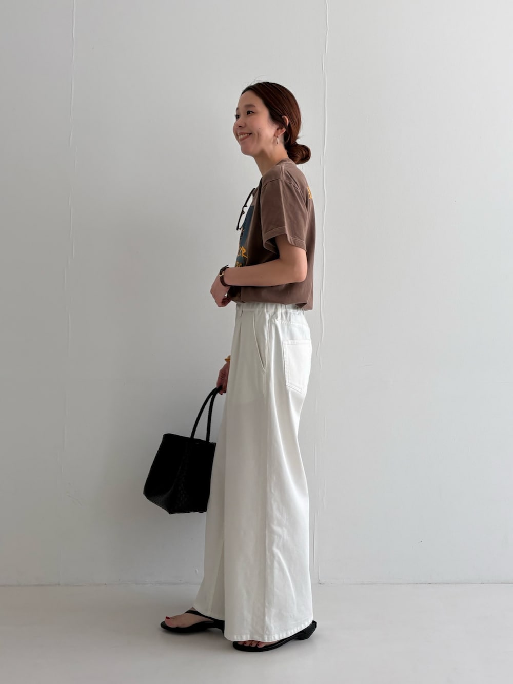 ホワイト系のデニムパンツ、ブラウン系のTシャツ/カットソー、ブラック系のサンダルを着用したレディースの春コーディネートの2枚目の写真