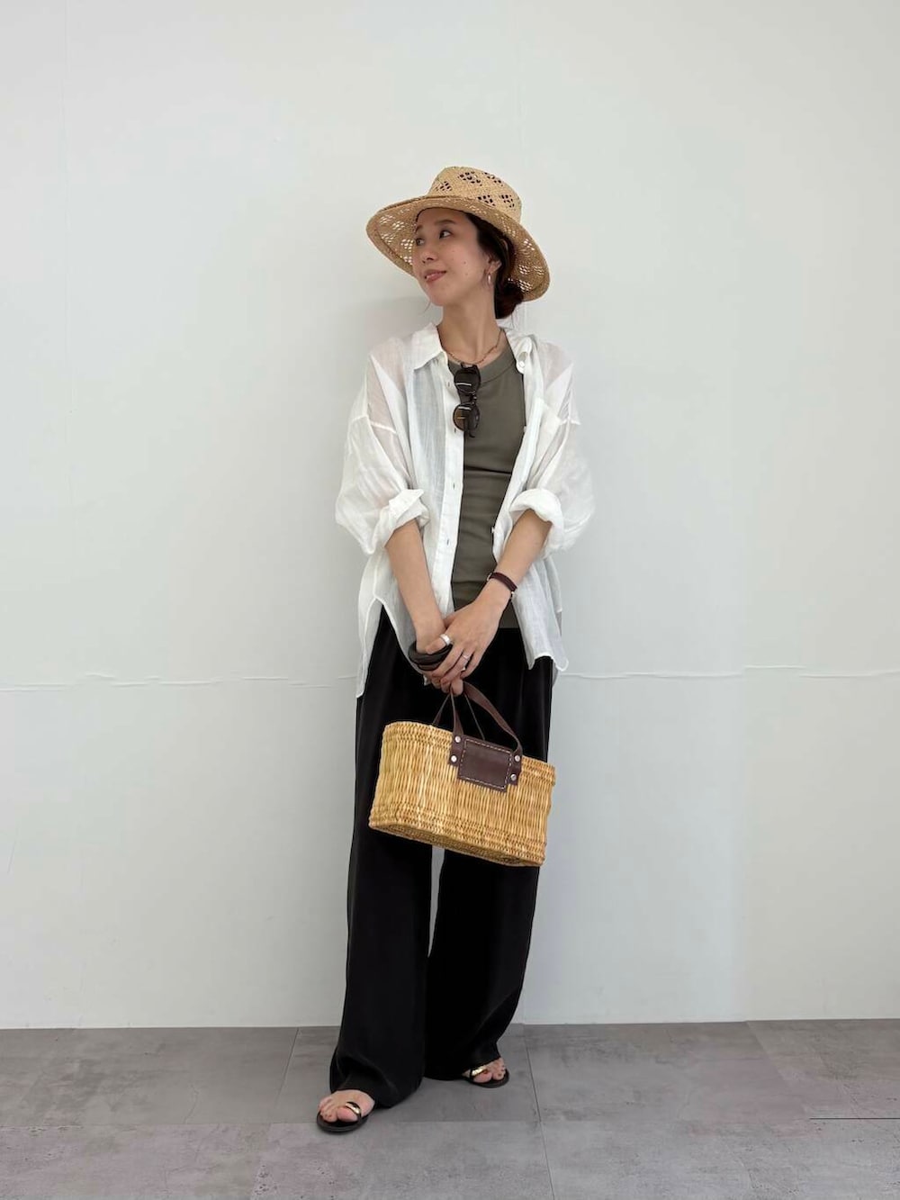 ブラウン系のかごバッグ、ホワイト系のシャツ/ブラウス、ブラック系のサンダルを着用したレディースの夏コーディネートの2枚目の写真