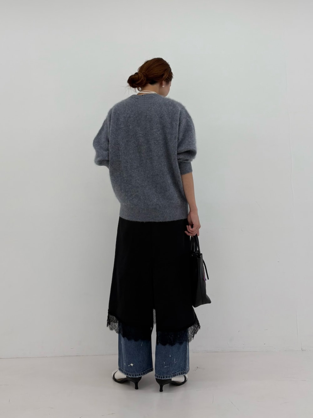 グレー系のニット/セーター、ブラック系のワンピース、ブルー系のデニムパンツを着用したレディースの秋コーディネートの3枚目の写真