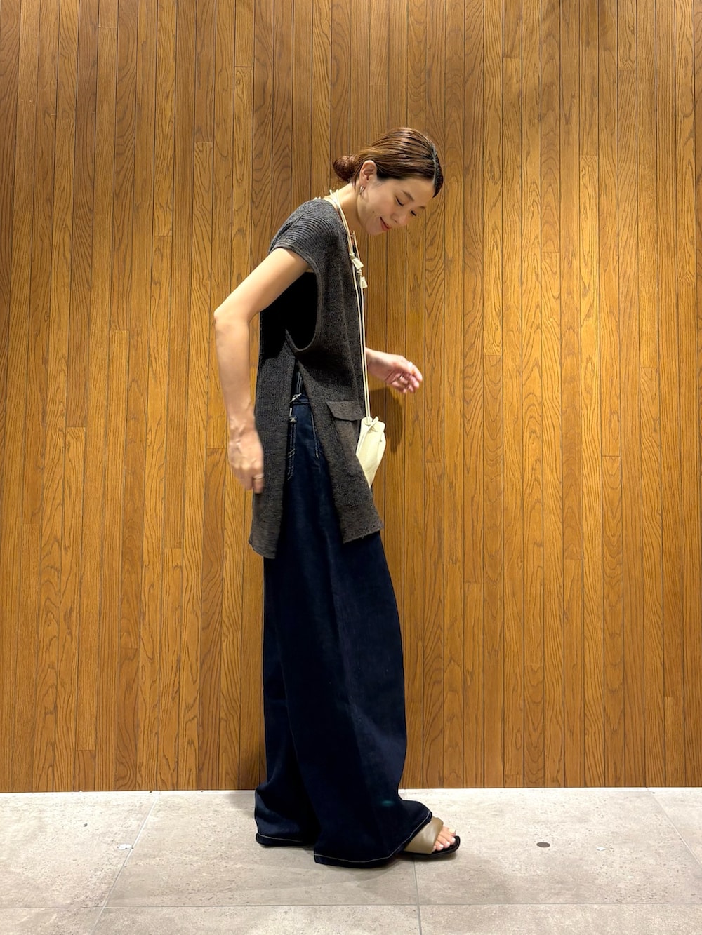 ブラック系のデニムパンツ、ブラック系のニット/セーター、ホワイト系のポーチを着用したレディースの夏コーディネートの2枚目の写真