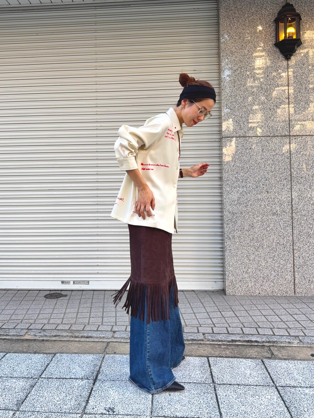 ホワイト系のTシャツ/カットソー、ブラウン系のスカート、ブルー系のデニムパンツを着用したレディースの秋コーディネートの2枚目の写真