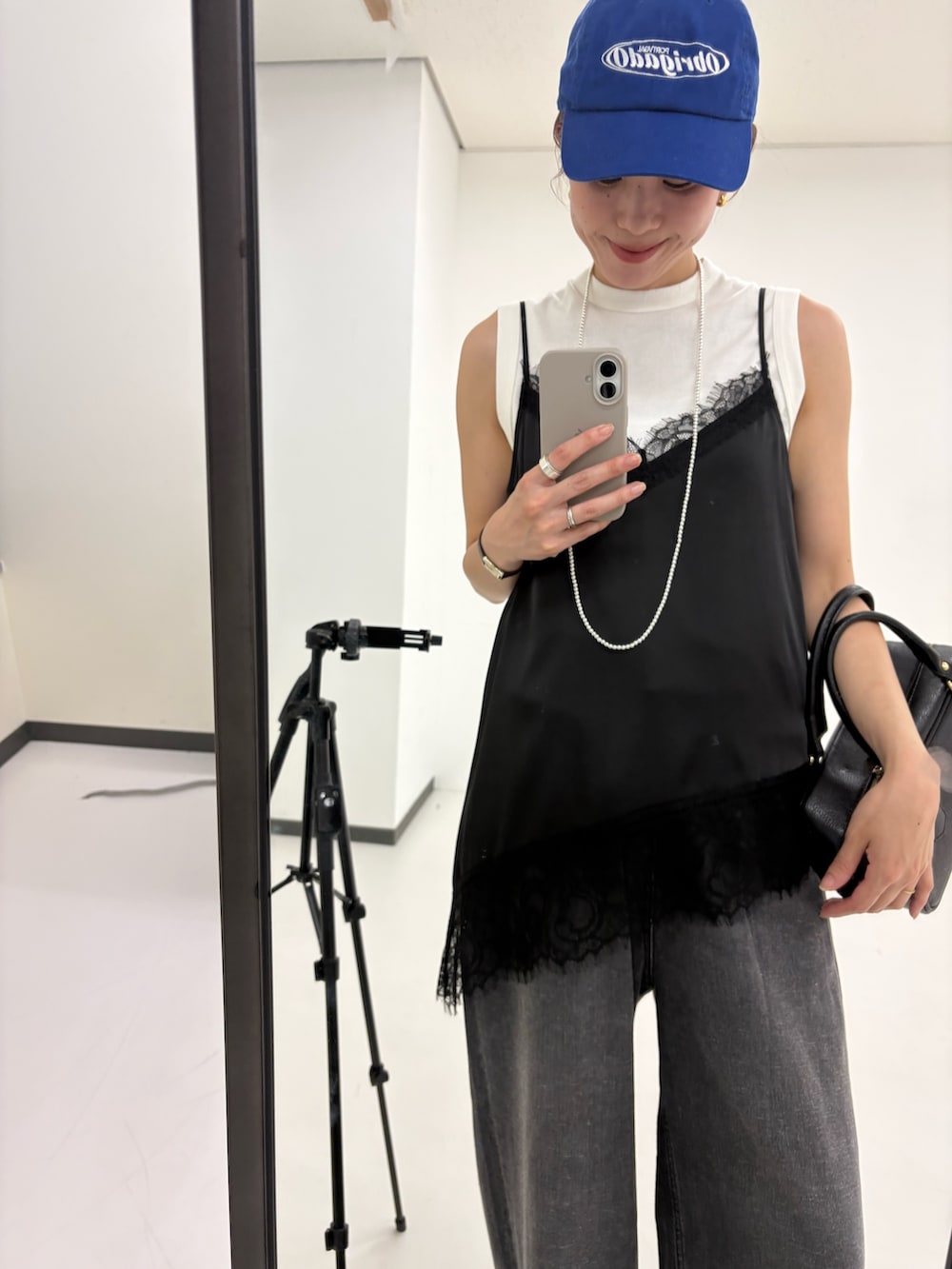 ブラック系のキャミソール、ホワイト系のタンクトップ、ブラック系のデニムパンツを着用したレディースの夏コーディネートの6枚目の写真
