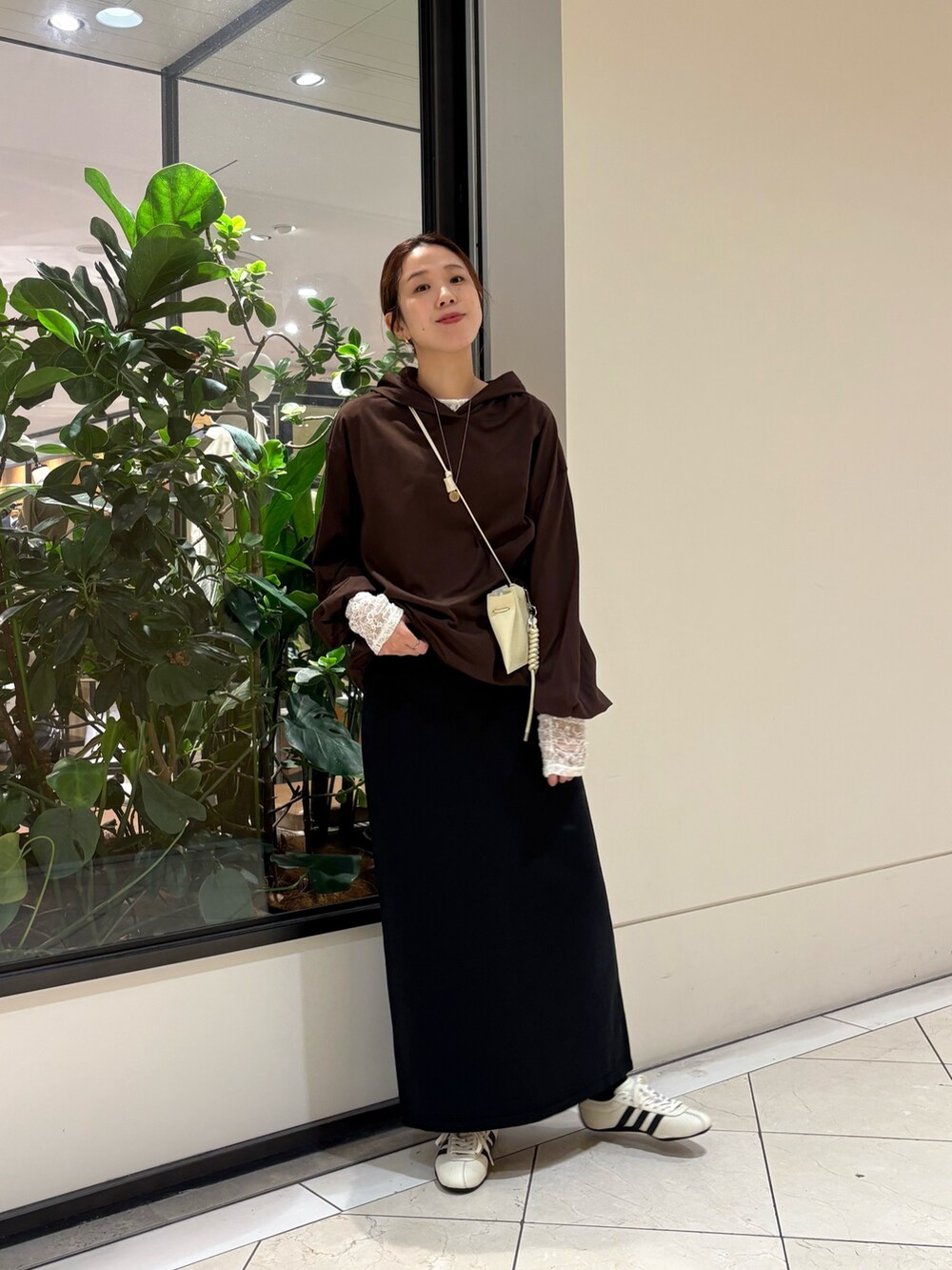 ブラウン系のパーカー、ホワイト系のスニーカー、ブラック系のスカートを着用したレディースの秋コーディネートの5枚目の写真