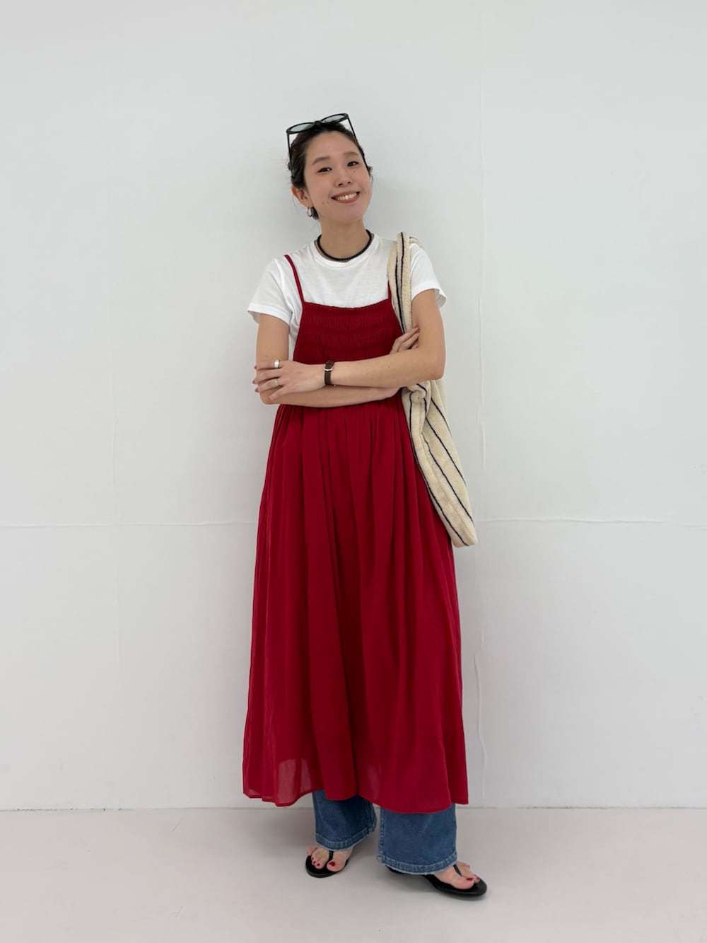 レッド系のワンピース、ホワイト系のトートバッグ、ブルー系のデニムパンツを着用したレディースの春コーディネートの4枚目の写真