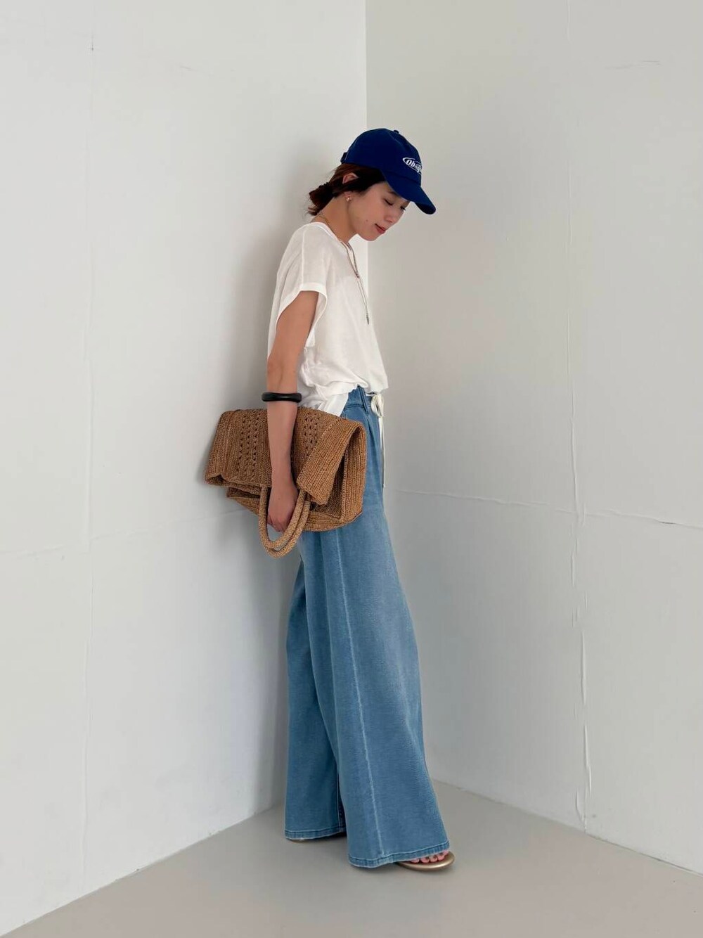 ホワイト系のキャミソール、ブルー系のデニムパンツ、ホワイト系のニット/セーターを着用したレディースの夏コーディネートの2枚目の写真