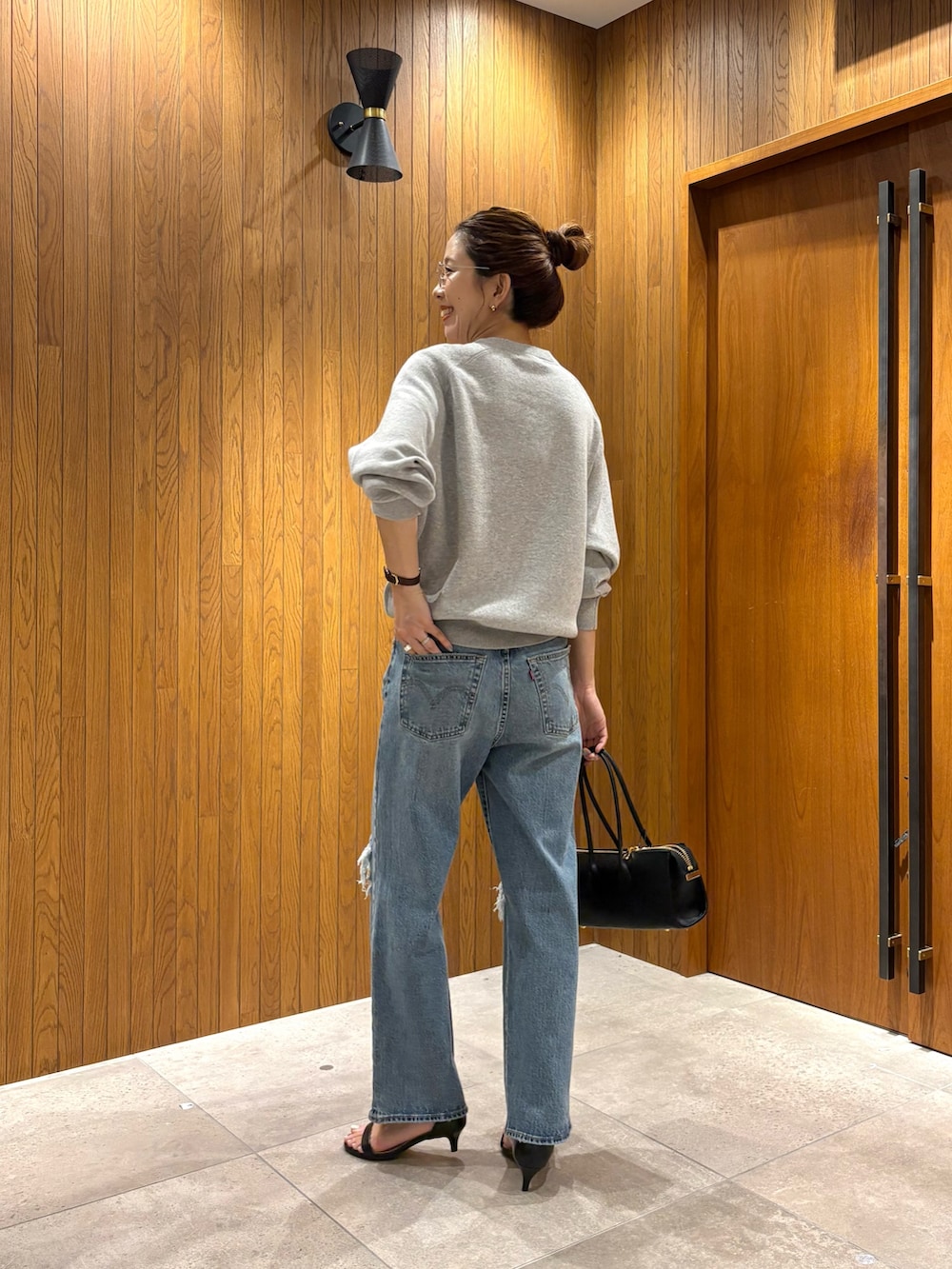 ブルー系のデニムパンツ、グレー系のニット/セーター、ブラック系のショルダーバッグを着用したレディースの秋コーディネートの3枚目の写真