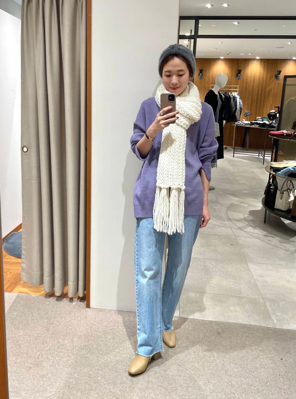 ブルー系のデニムパンツ、ベージュ系のブーツ、パープル系のニット/セーターを着用したレディースの冬コーディネートの2枚目の写真