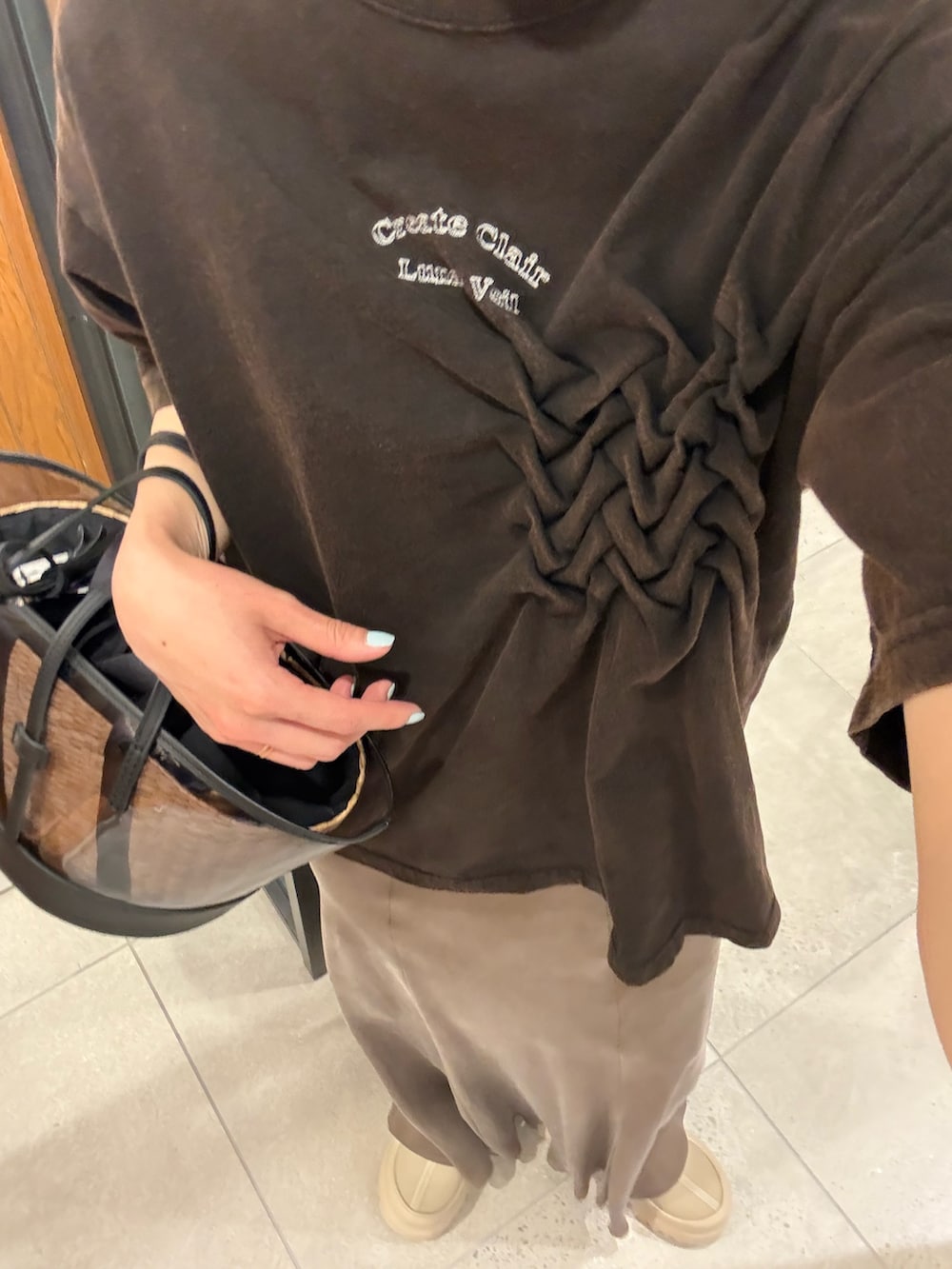 ブラウン系のスカート、ブラック系のかごバッグを着用したレディースの春コーディネートの6枚目の写真