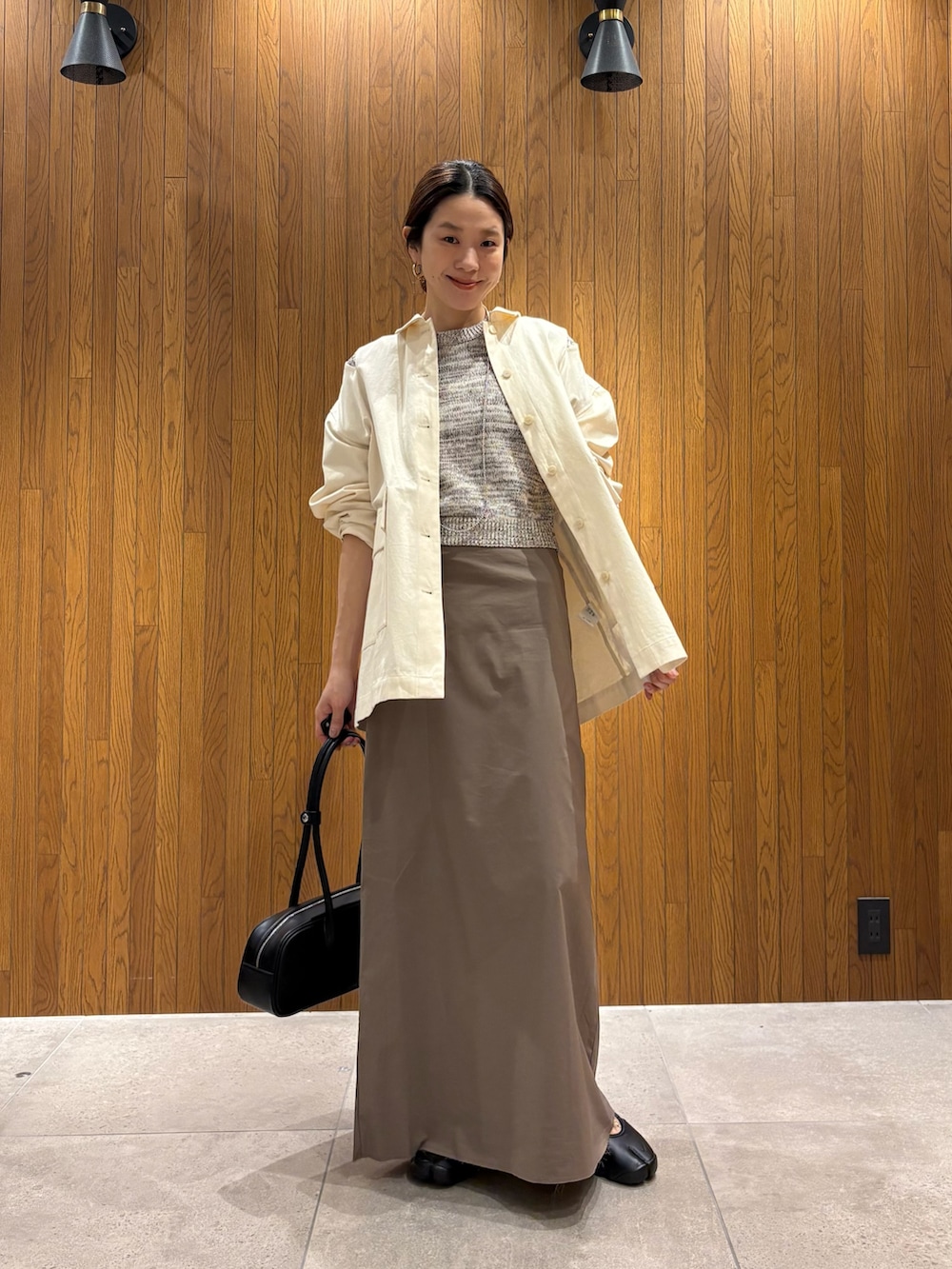 グレー系のスカート、その他のニット/セーター、ブラック系のスニーカーを着用したレディースの春コーディネートの4枚目の写真