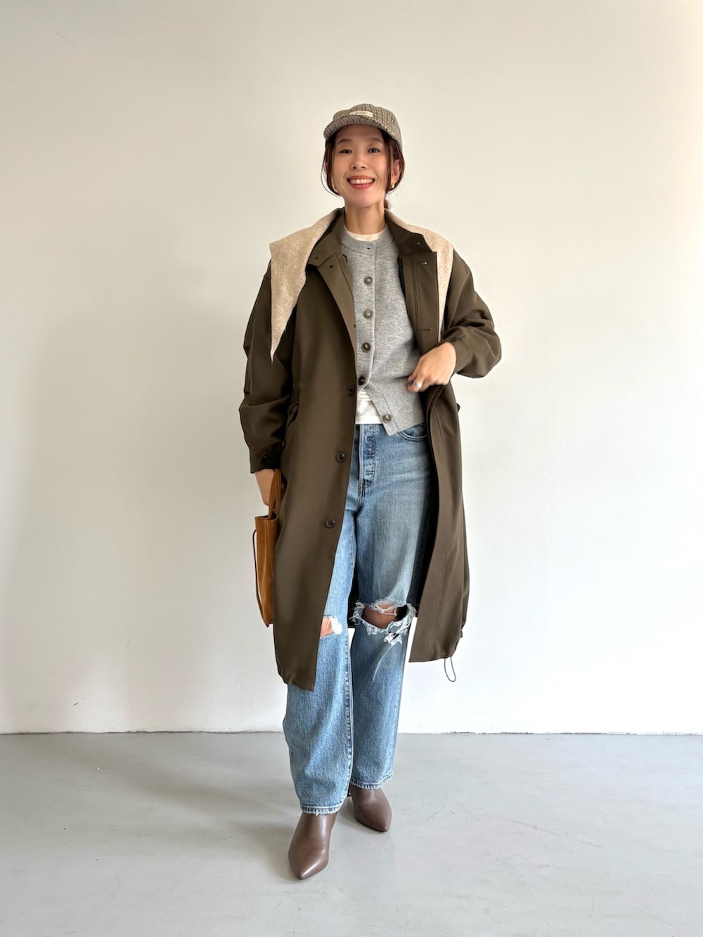 ブルー系のデニムパンツ、ベージュ系のトートバッグ、ホワイト系のTシャツ/カットソーを着用したレディースの冬コーディネートの2枚目の写真