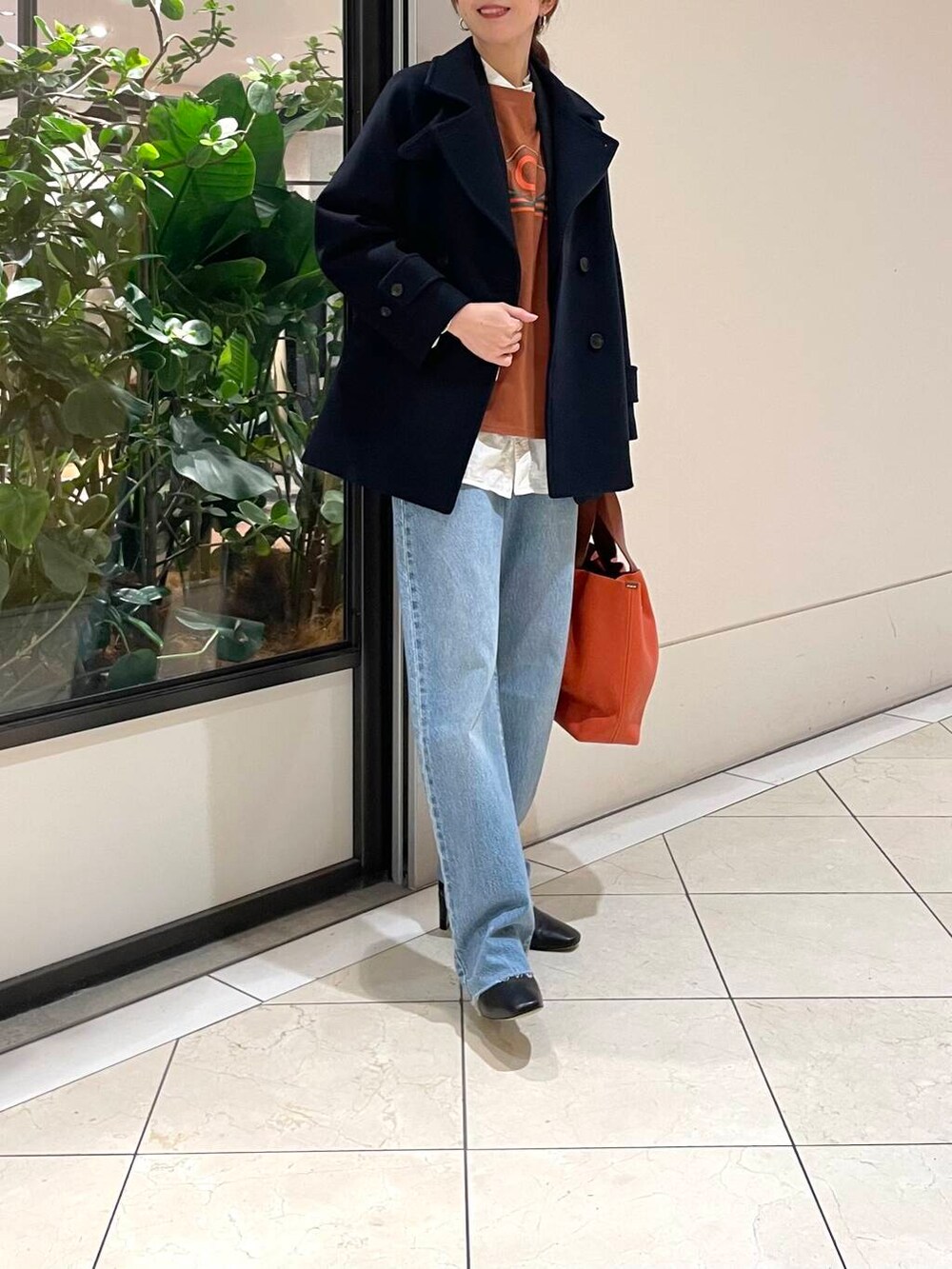 ブルー系のピーコート、ブルー系のデニムパンツ、ブラック系のブーツを着用したレディースの冬コーディネートの2枚目の写真