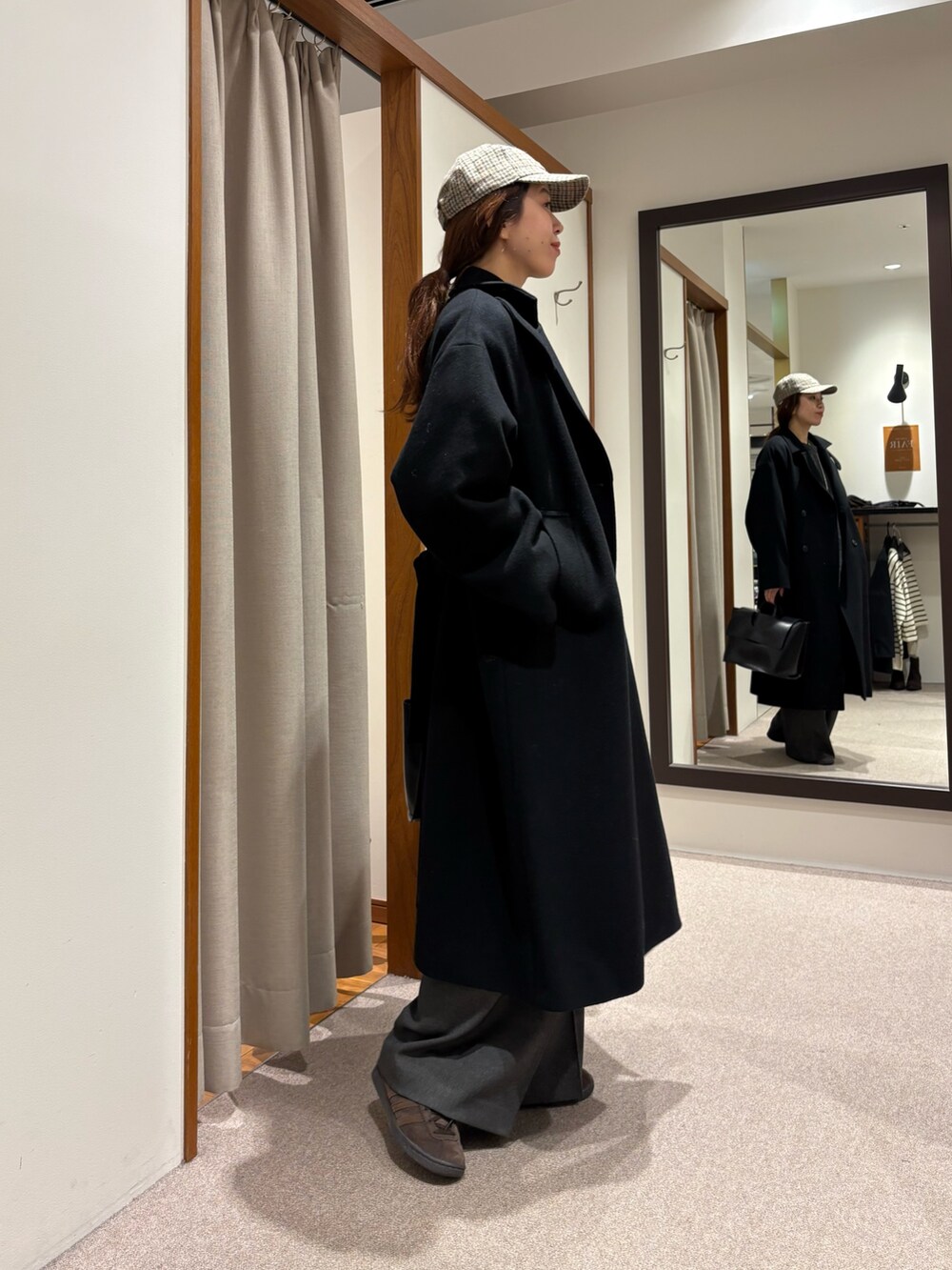 ブラック系のチェスターコート、グレー系のその他パンツ、ブラック系のハンドバッグを着用したレディースの冬コーディネートの2枚目の写真