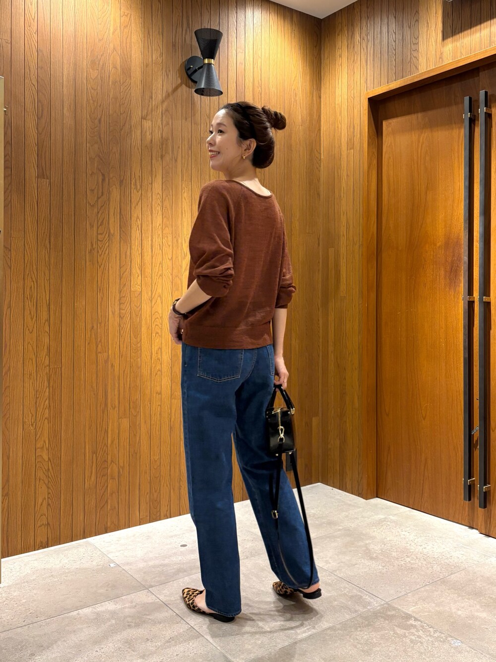 ブルー系のデニムパンツ、ブラック系のショルダーバッグ、ブラウン系のカーディガン/ボレロを着用したレディースの秋コーディネートの4枚目の写真