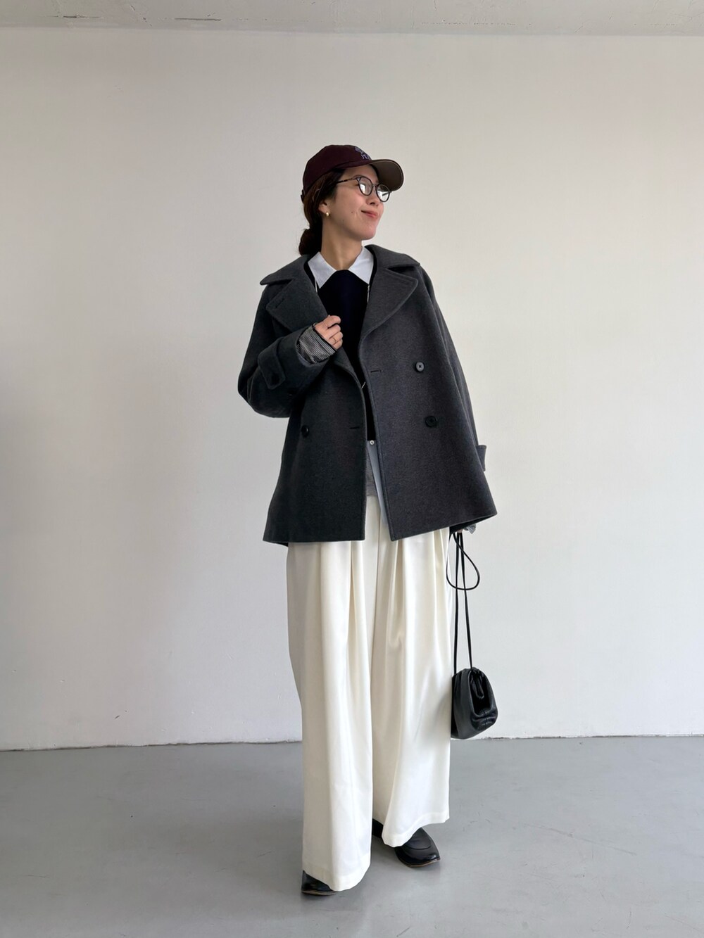 グレー系のピーコート、ホワイト系のその他パンツ、シルバー系のショルダーバッグを着用したレディースの冬コーディネートの2枚目の写真