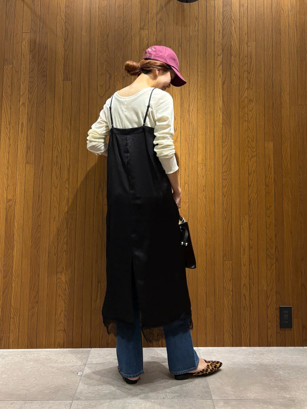 ブラック系のワンピース、ブルー系のデニムパンツ、ブラック系のショルダーバッグを着用したレディースの秋コーディネートの4枚目の写真
