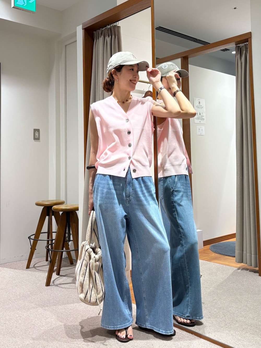 ブルー系のデニムパンツ、ピンク系のベスト、ホワイト系のハンドバッグを着用したレディースの夏コーディネートの5枚目の写真