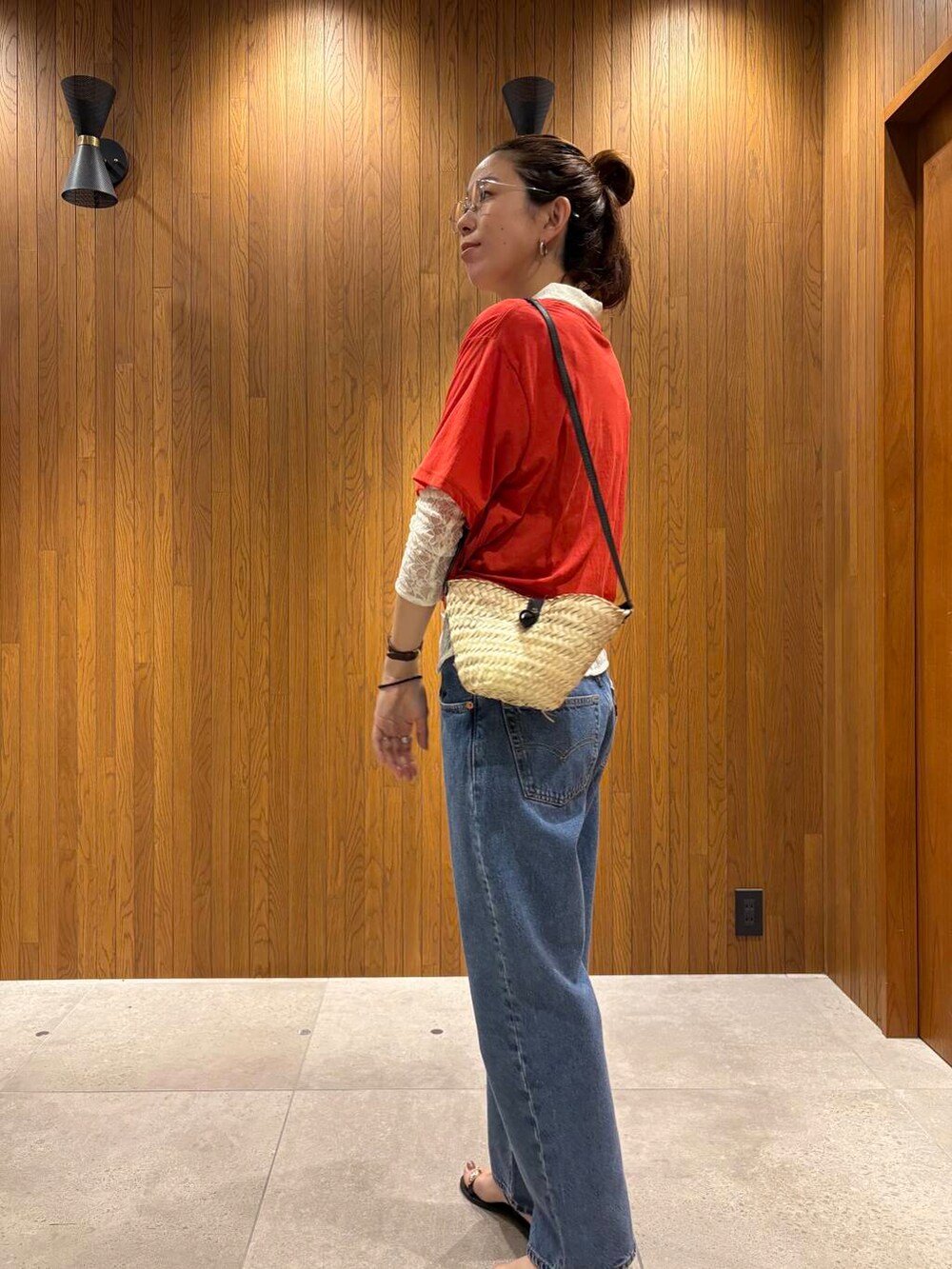 ブルー系のデニムパンツ、ブラック系のサンダル、レッド系のTシャツ/カットソーを着用したレディースの夏コーディネートの6枚目の写真