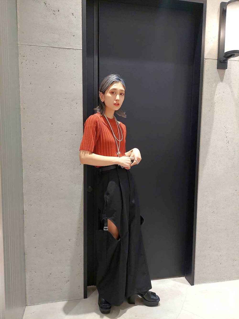 ブラック系のサンダル、ホワイト系のワンピース、オレンジ系のニット/セーターを着用したレディースの春コーディネートの2枚目の写真