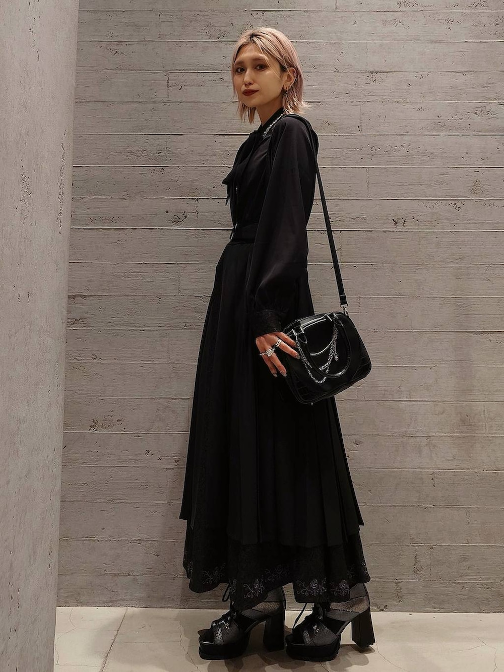 シルバー系のブーツ、ブラック系のショルダーバッグ、ブラック系のワンピースを着用したレディースの春コーディネートの2枚目の写真