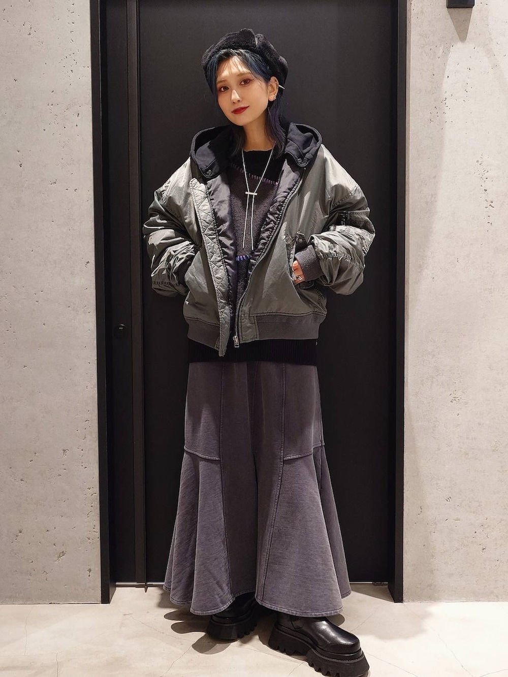 グレー系のスカート、ブラック系のショルダーバッグ、ブラック系のブーツを着用したレディースの冬コーディネートの2枚目の写真