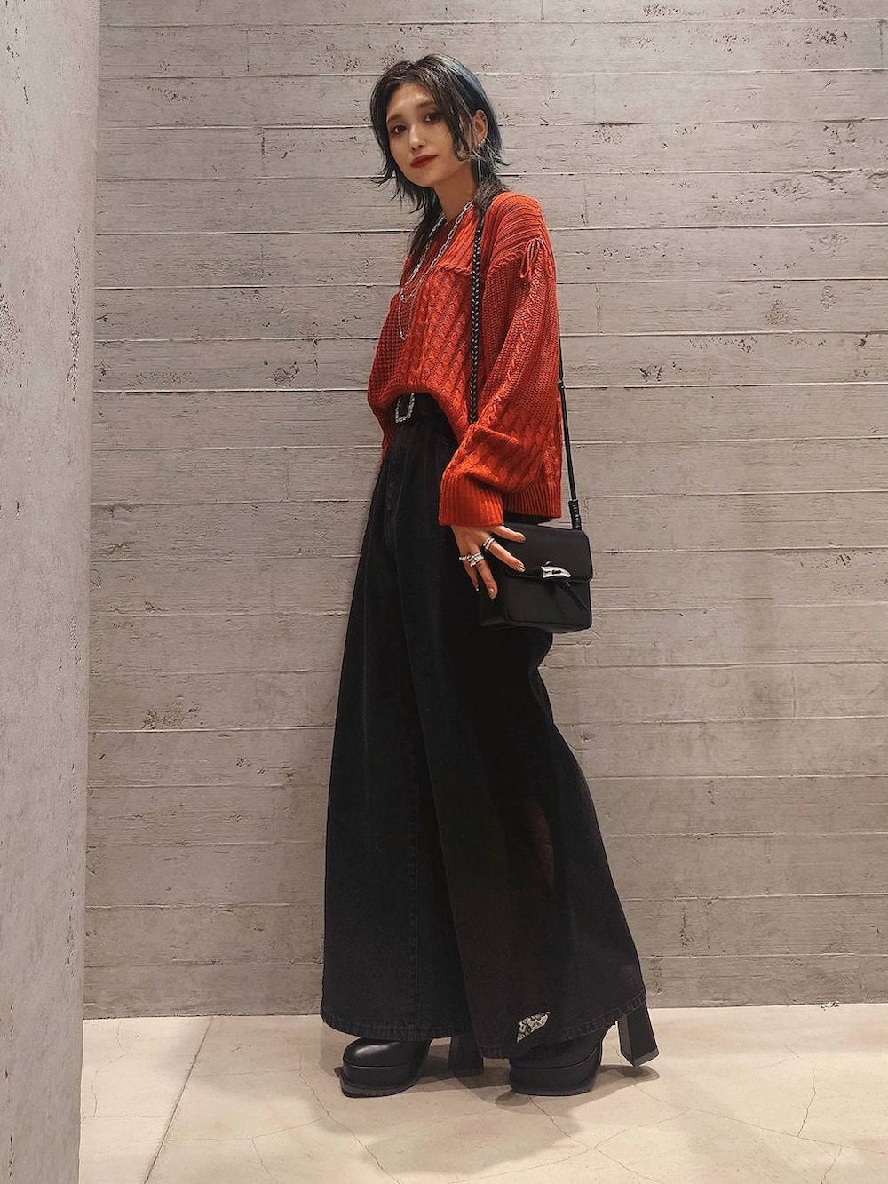 オレンジ系のニット/セーター、ブラック系のデニムパンツ、ブラック系のショルダーバッグを着用したレディースの秋コーディネートの2枚目の写真