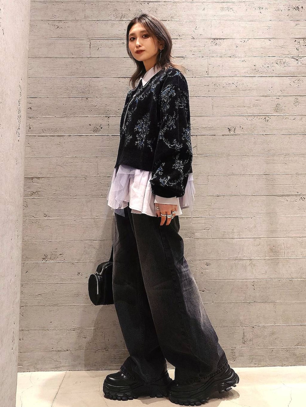 ブラック系のデニムパンツ、ブラック系のハンドバッグ、グレー系のシャツ/ブラウスを着用したレディースの秋コーディネートの2枚目の写真