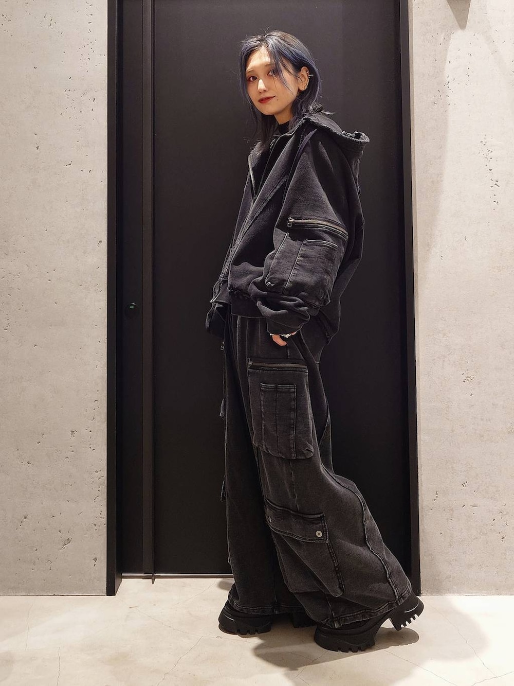 ブラック系のパーカー、ブラック系のカーゴパンツ、ブラック系のブーツを着用したレディースの秋コーディネートの2枚目の写真