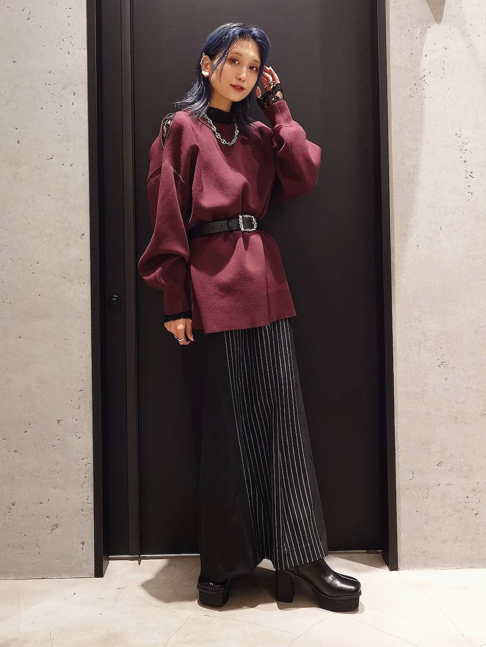 ブラック系のチェスターコート、ブラック系のTシャツ/カットソー、レッド系のニット/セーターを着用したレディースの秋コーディネートの2枚目の写真