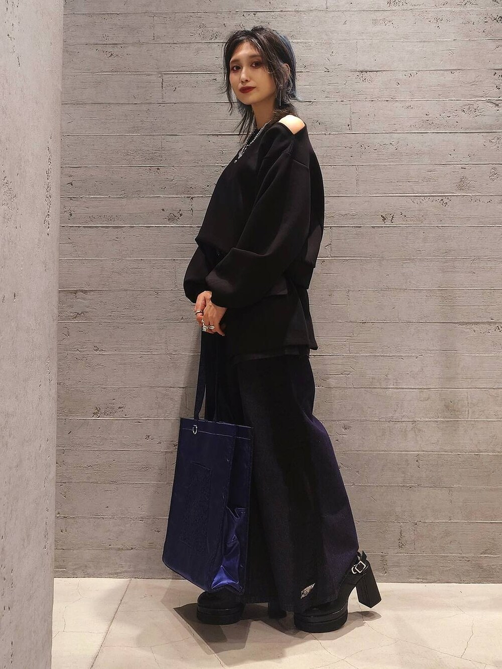 ブルー系のトートバッグ、ブラック系のサンダル、ブルー系のデニムパンツを着用したレディースの秋コーディネートの2枚目の写真