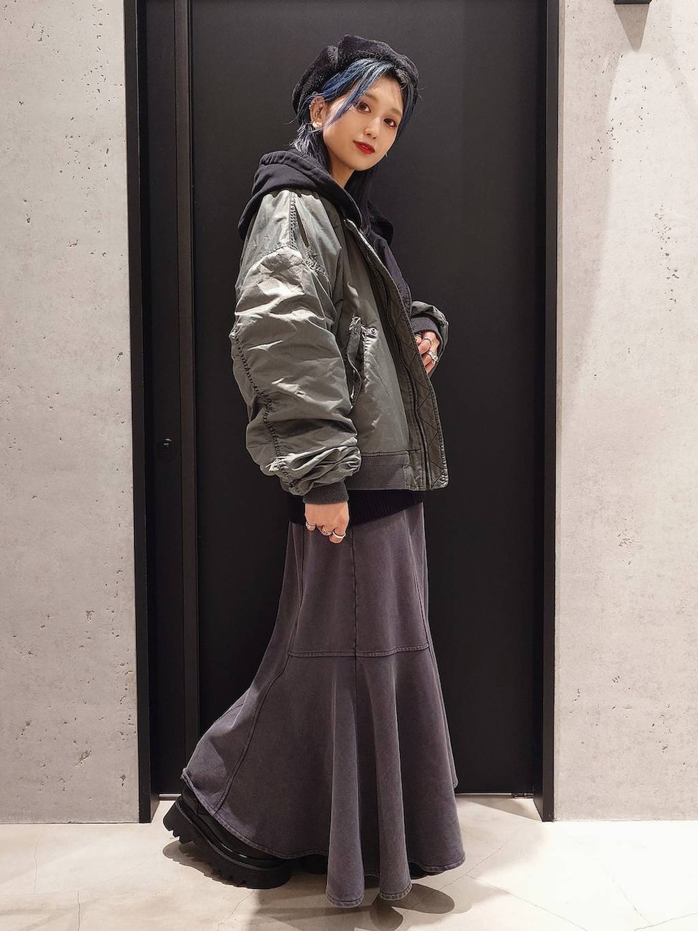 グレー系のスカート、ブラック系のショルダーバッグ、ブラック系のブーツを着用したレディースの冬コーディネートの3枚目の写真