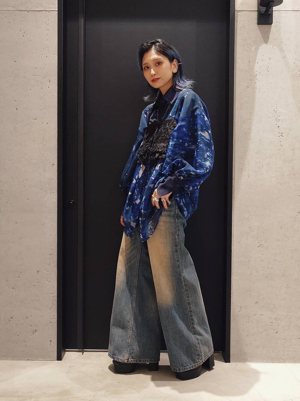 シルバー系のショルダーバッグ、ブルー系のデニムパンツ、ブラック系のブーツを着用したレディースの秋コーディネートの2枚目の写真