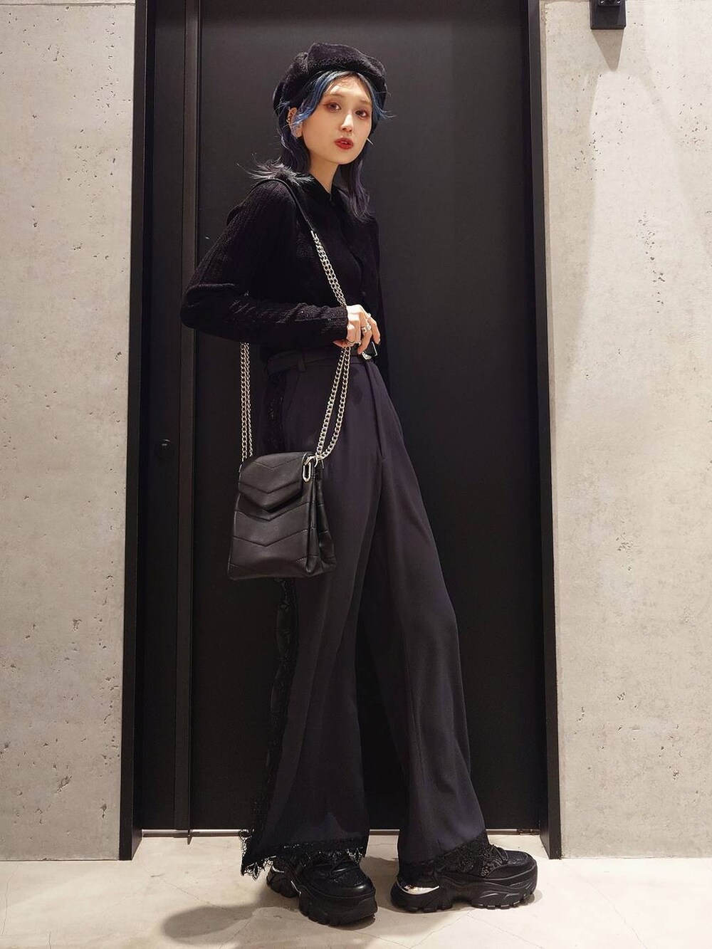 ブラック系のショルダーバッグ、ホワイト系のトレンチコート、ブラック系のスニーカーを着用したレディースの冬コーディネートの2枚目の写真