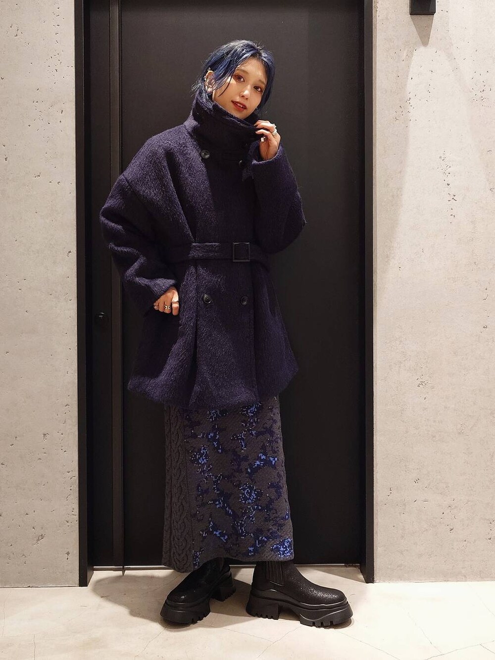 グレー系のニット/セーター、ブラック系のトートバッグ、グレー系のスカートを着用したレディースの秋コーディネートの2枚目の写真