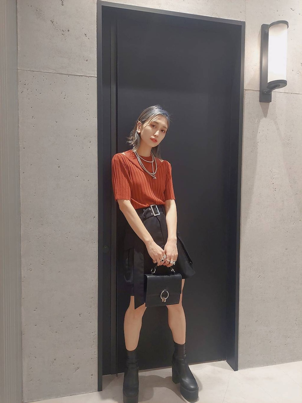 ブラック系のその他パンツ、ブラック系のショルダーバッグ、オレンジ系のニット/セーターを着用したレディースの春コーディネートの2枚目の写真