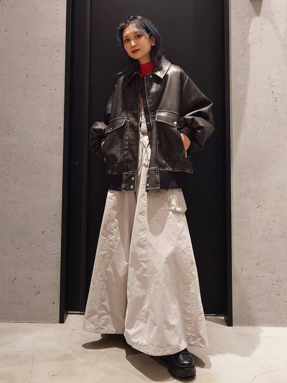 レッド系のニット/セーター、ブラック系のスニーカー、ブラック系のショルダーバッグを着用したレディースの冬コーディネートの2枚目の写真