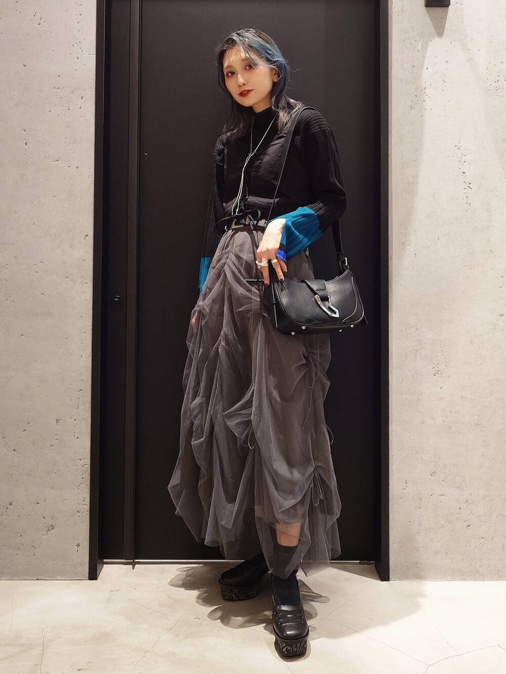 ブラック系のニット/セーター、ブラック系のショルダーバッグ、ベージュ系のトレンチコートを着用したレディースの冬コーディネートの2枚目の写真