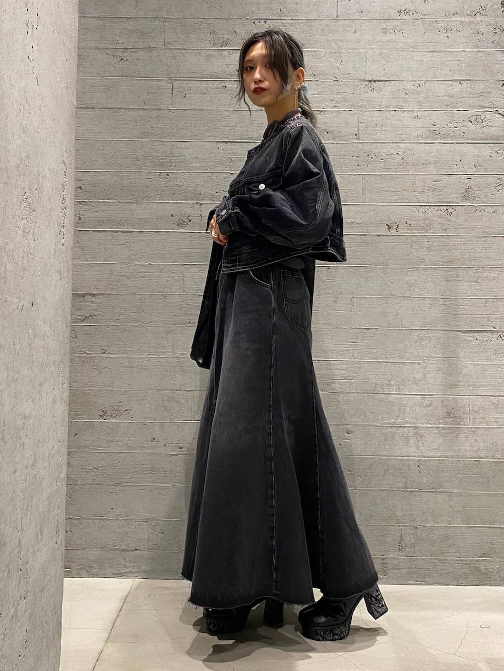 ブラック系のデニムジャケット、ブラック系のデニムスカート、グレー系のブーツを着用したレディースの秋コーディネートの2枚目の写真