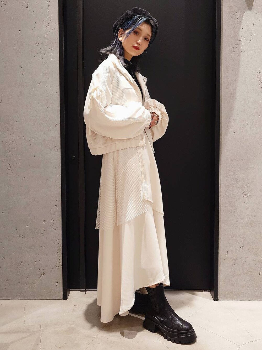 ブラック系のニット/セーター、ブラック系のブーツ、ホワイト系のスカートを着用したレディースの冬コーディネートの2枚目の写真