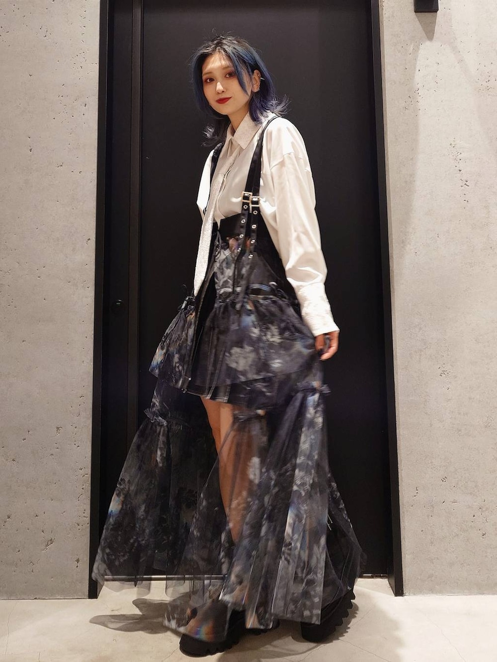 グレー系のスカート、ブラック系のショルダーバッグ、ブラック系のブーツを着用したレディースの冬コーディネートの3枚目の写真